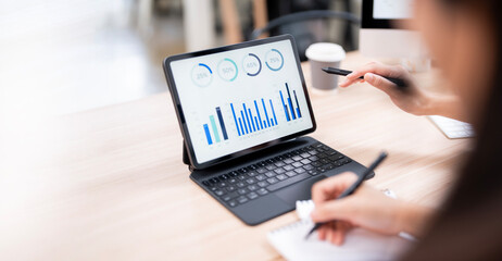 business meeting or a student study session. One person points to a bar graph on a tablet screen