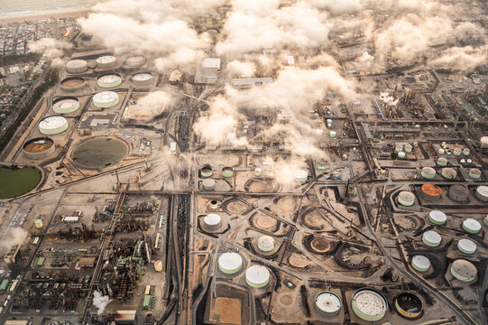 Aerial view of a large industrial zone with factories, storage tanks, and chimneys near the port area in Los Angeles, showcasing logistics, manufacturing, and heavy industry infrastructure