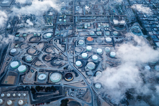 Aerial view of a large industrial zone with factories, storage tanks, and chimneys near the port area in Los Angeles, showcasing logistics, manufacturing, and heavy industry infrastructure