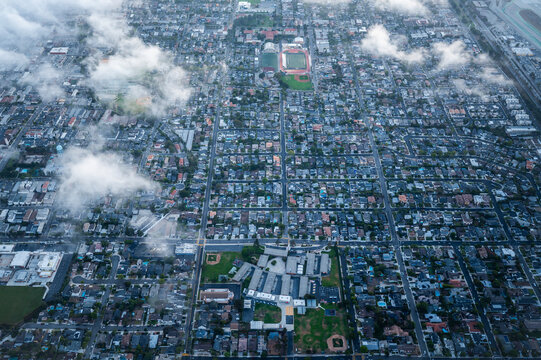 Aerial drone view of busy urban intersection surrounded by grid-pattern streets, single-family homes, and commercial buildings in Los Angeles suburbs