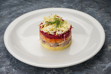 Shuba salad with herring and beets in a white plate on a gray background