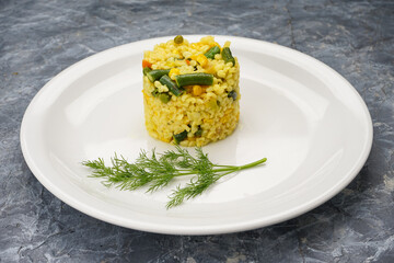 Bulgur with vegetables in a white plate on a gray concrete background