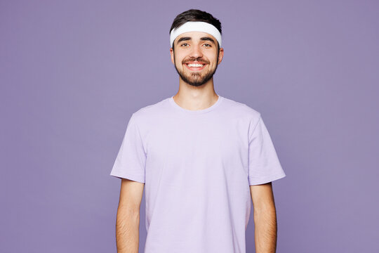 Young smiling happy strong fitness trainer instructor sporty man sportsman he wear headband t-shirt training in home gym look camera isolated on plain purple background. Workout sport fit abs concept. - Powered by Adobe