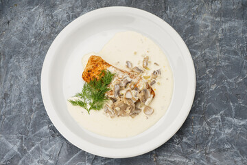 chop with creamy mushroom sauce in a white plate on a gray concrete background