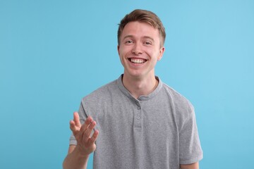 Handsome man laughing on light blue background. Positive emotion