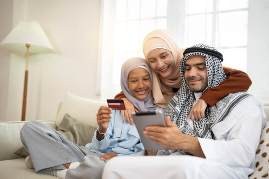 Muslim family shopping online with a credit card on their digital tablet in living room at home
