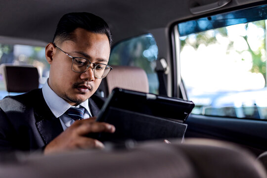 Businessman In Suit Working On Tablet Inside Car With Focused Expression