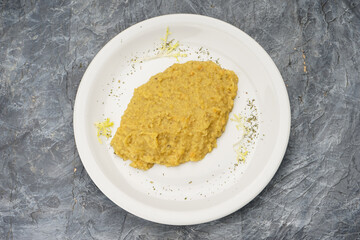 Wheat porridge seasoned with butter in a white plate on a gray background