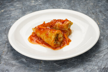 Ukrainian dish cabbage rolls in a white plate on a gray concrete background