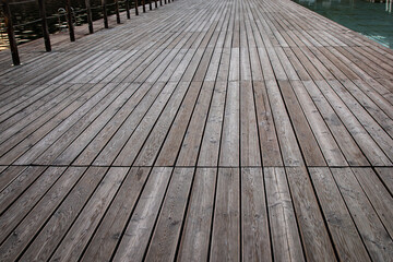 A low-angle, wide shot of a weathered wooden deck or walkway with planks laid in a geometric pattern