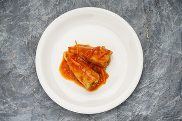 Ukrainian dish cabbage rolls in a white plate on a gray background