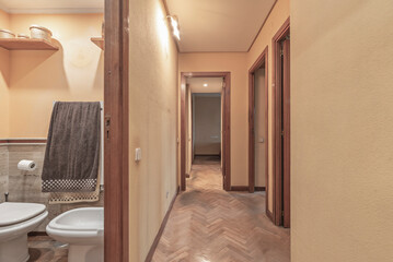 A narrow hallway design with textured plasterboard and warm lighting transforms a functional space into a welcoming gallery