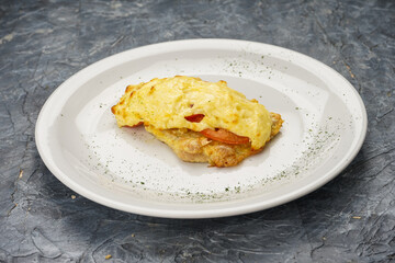 chicken chop with tomato and cheese in a white plate on a gray concrete background