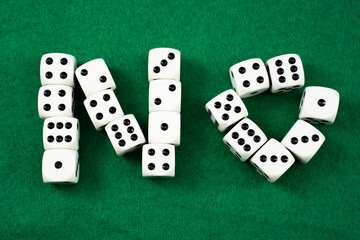 White dice with black dots are creatively arranged to spell out the word no against a vibrant green surface. The playful setup highlights the fun aspect of gaming or decision-making.