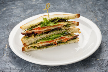 two sandwiches with fish and greens in a white plate on a background