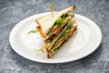 two sandwiches with fish and greens on a white plate
