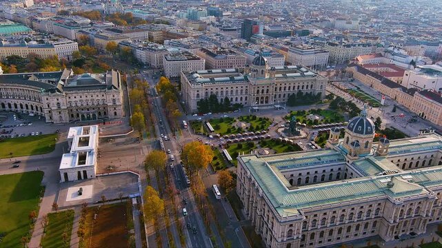 4K drone view of Vienna&rsquo;s Ringstrasse: Hofburg Neue Burg and the twin museums frame Maria-Theresien-Platz in warm autumn light, with tree lined boulevards and city traffic around the historic core.