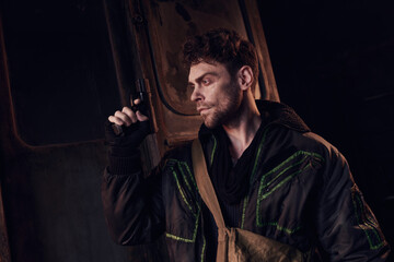 A determined young man stands ready for challenges in a bleak, dystopian environment.