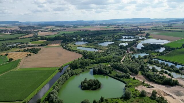 Aerial view of the Marienberg ponds with their unique shapes surrounded by patchwork fields of vibrant green and golden brown, Pattensen, Niedersachsen, Germany.