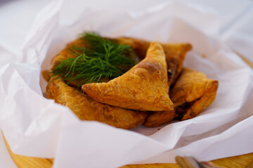 Savory pastries served on a wooden platter with fresh herbs on linen