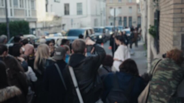 Celebrity waving to paparazzi on city street