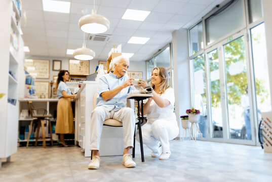 Female pharmacist checking an elderly man blood pressure in a pharmacy and consults him about the appropriate medication. - Powered by Adobe