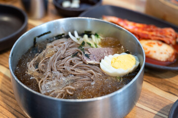Korean Naengmyeon Cold Noodles with Egg and Vegetables in Chilled Broth.