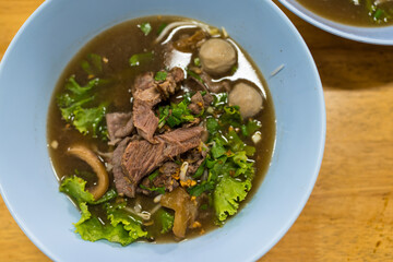 Stewed beef and offal noodle soup, Thai stew food and vegetables in bowl on wood table