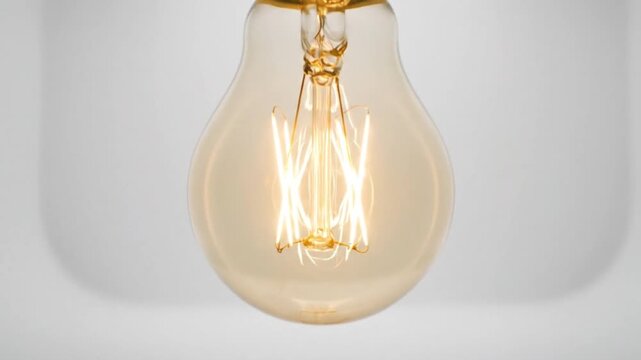 A close-up shot of a vintage-style light bulb illuminates against a soft, white backdrop, symbolizing ideas and innovation with its warm, glowing filaments.