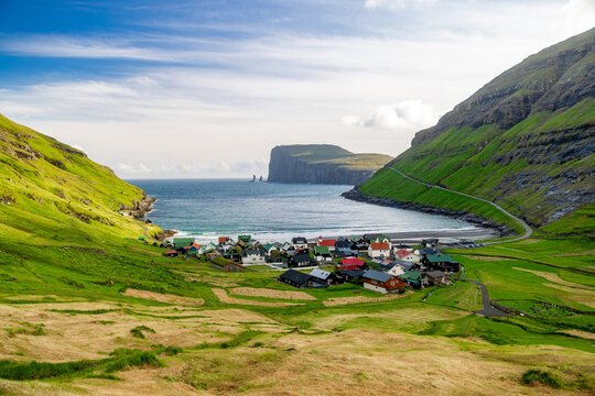 View of a quaint village nestled between verdant mountains and the serene ocean, with colorful rooftops contrasting against the green hillsides, Tj&Atilde;&cedil;rnuv&Atilde;&shy;k, Streymoy, Faroes, Denmark.
