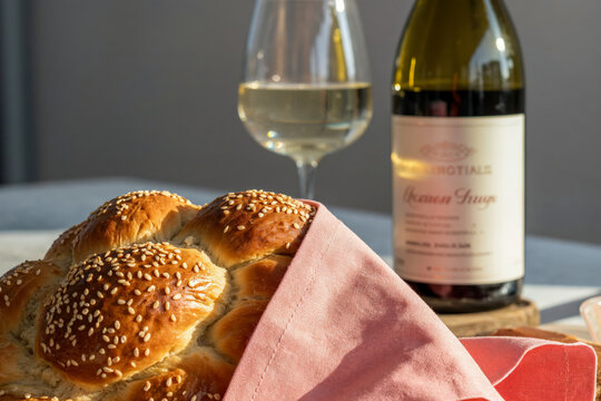 Freshly baked challah with wine on sunlit table, Rosh Hashanah celebration - Powered by Adobe