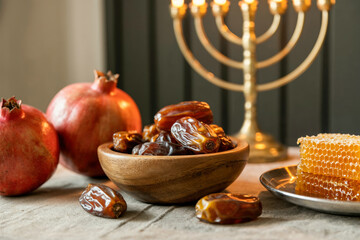 Festive table with dates, pomegranates, honeycomb, and menorah candleholder, Rosh Hashanah celebration