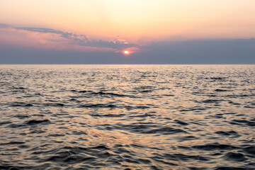 Fototapeta premium calm sea horizon under sunset sky. minimal composition with warm sky gradient under calm sea surface with gentle waves. nature