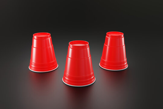 Three upside down red disposable plastic cups on a black background. Illustration of the concept of guessing, betting, unknown and games