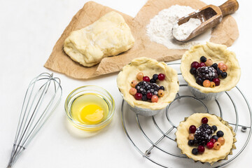 Dough and berries in baking cup on metal trivet.  Whisk and yolk in bowl.