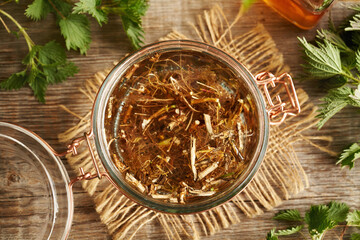 Fresh nettle root macerating in alcohol to prepare herbal tincture, top view