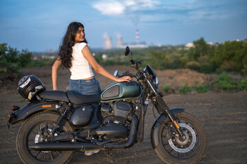 Strong independent Indian woman biker: beautiful girl, stylish rider, motorcycle adventure, elegant jacket, confident posture, powerful machine, free spirit, road journey, fearless attitude. © Ojas