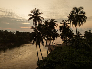 Aerial view of S&atilde;o Tom&eacute;&rsquo;s tropical coastline near S&atilde;o Jo&atilde;o dos Angolares, with turquoise waters, black volcanic rocks, and dense palm forest.