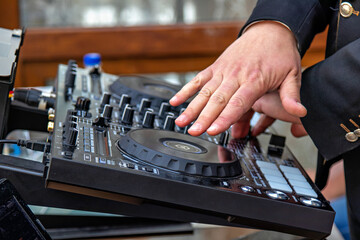 A person's hands operating a DJ mixer