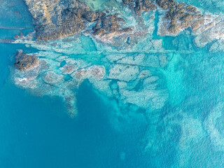 Aerial view of São Tomé’s tropical coastline near São João dos Angolares, with turquoise waters, black volcanic rocks, and dense palm forest.  
