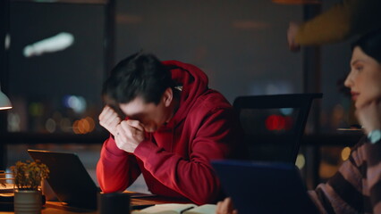 Shocked coworkers disappointed fail looking laptop at night workspace closeup.