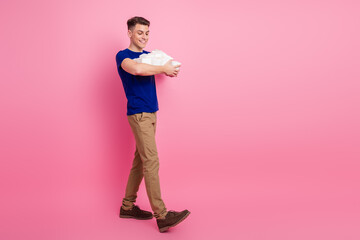 Happy young man holding gift boxes in casual outfit on pink background during summer advertising campaign