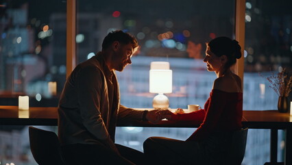 Flirting couple sitting dark restaurant in lamp light closeup. Smiling spouses