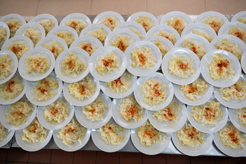 Overhead view of many plates filled with cabbage salad garnished with paprika, catering and food service concept