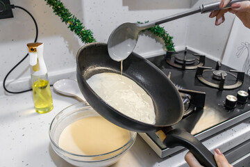 Pancakes are fried in a hot pan. Traditional homemade baking and cooking process.A series of home photos of the process of cooking pancakes in the kitchen. The pictures show different stages of the