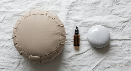 Flat lay of a meditation cushion, essential oil bottle, and calming stone on linen cloth