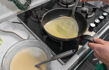 Pancakes are fried in a hot pan. Traditional homemade baking and cooking process.A series of home photos of the process of cooking pancakes in the kitchen. The pictures show different stages of the