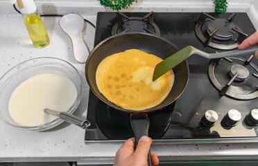 Pancakes are fried in a hot pan. Traditional homemade baking and cooking process.A series of home photos of the process of cooking pancakes in the kitchen. The pictures show different stages of the