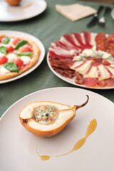 Delicious baked pear stuffed with Roquefort cheese, walnuts and honey, served with pizza and cold cuts