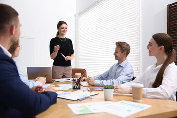 Business coach giving presentation to group of people in office